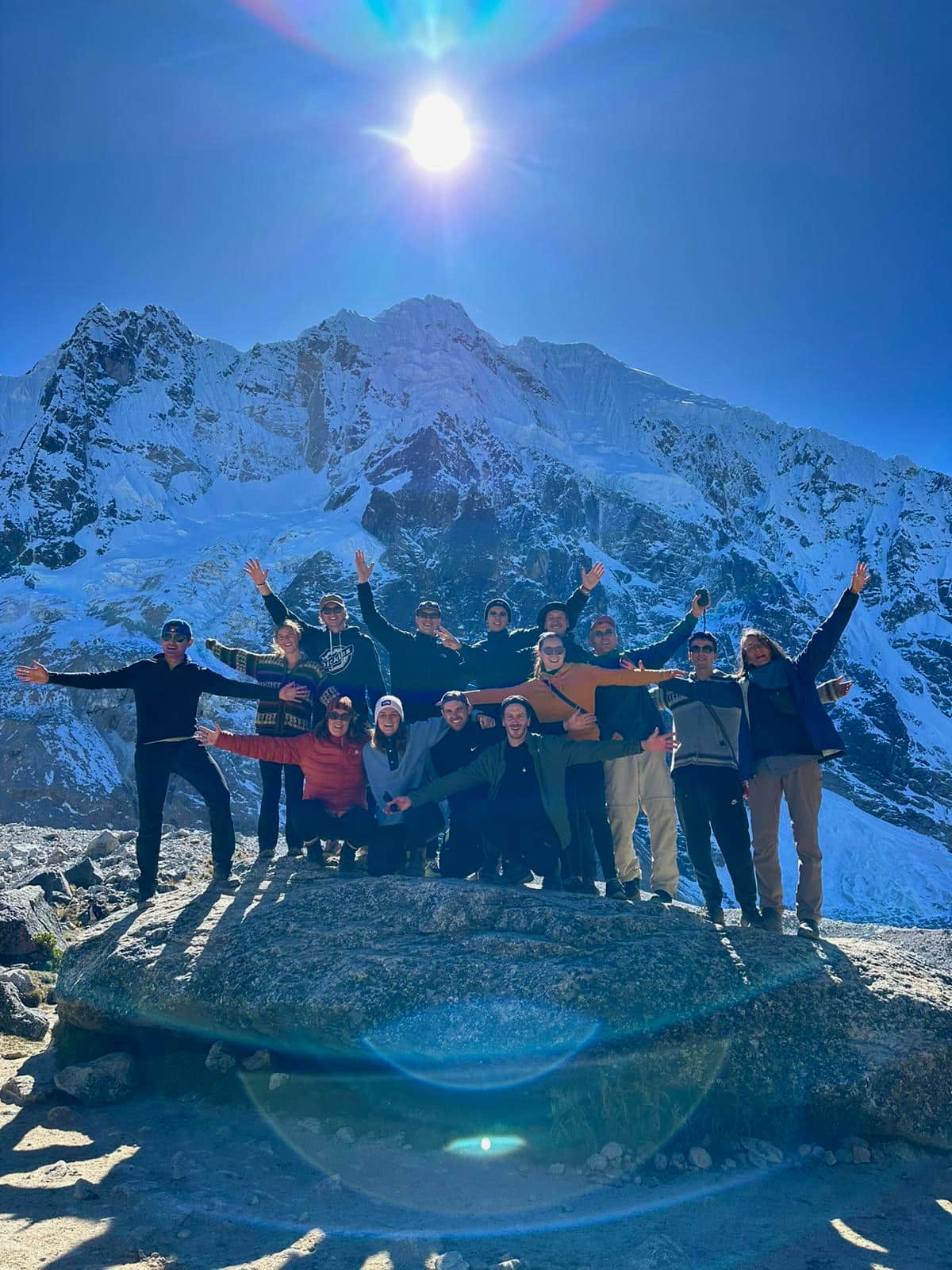 Konex group with arms raised in front of a snow-covered mountain face