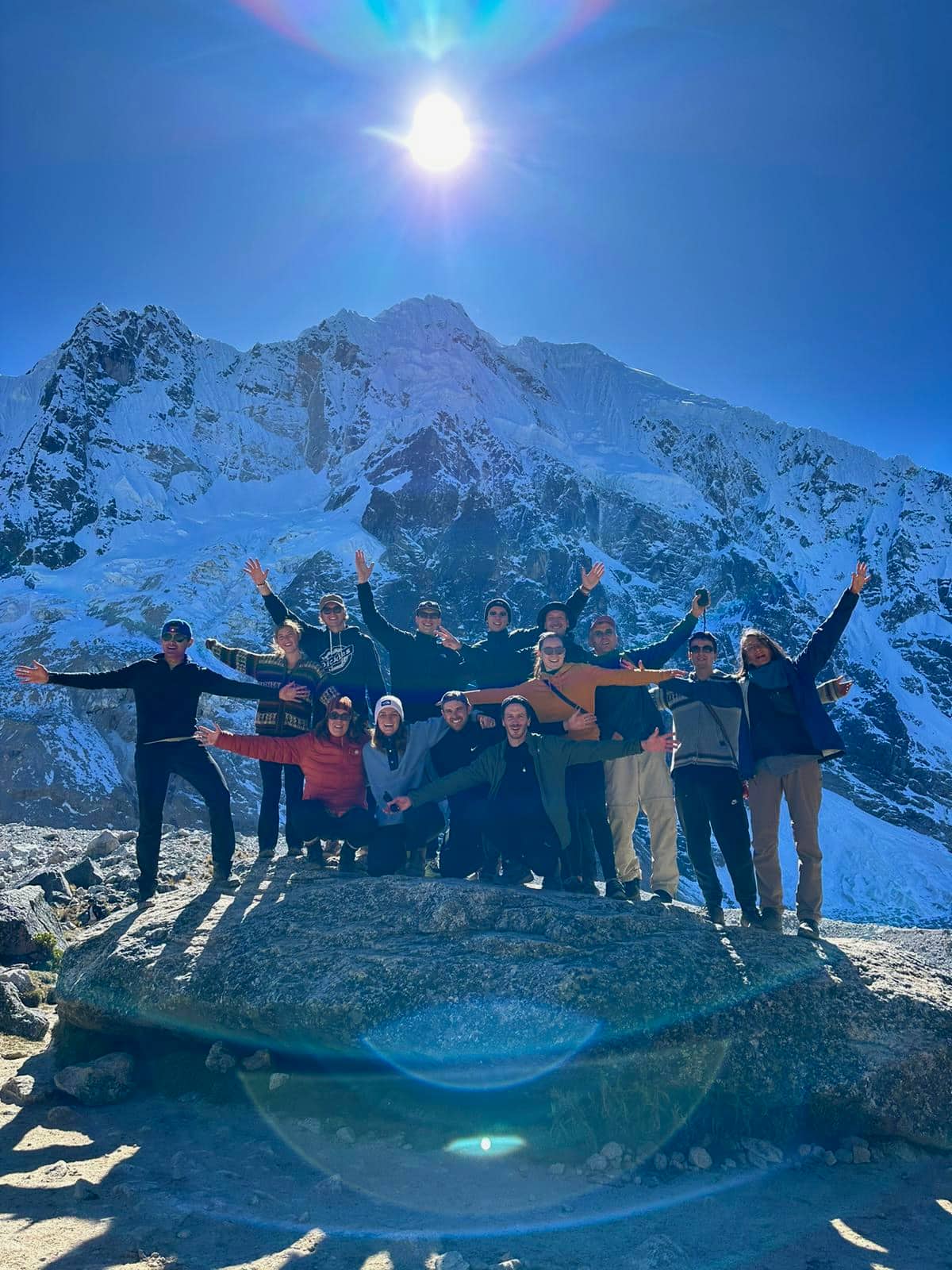 A Konex retreat group with arms raised in front of a snow-covered mountain face